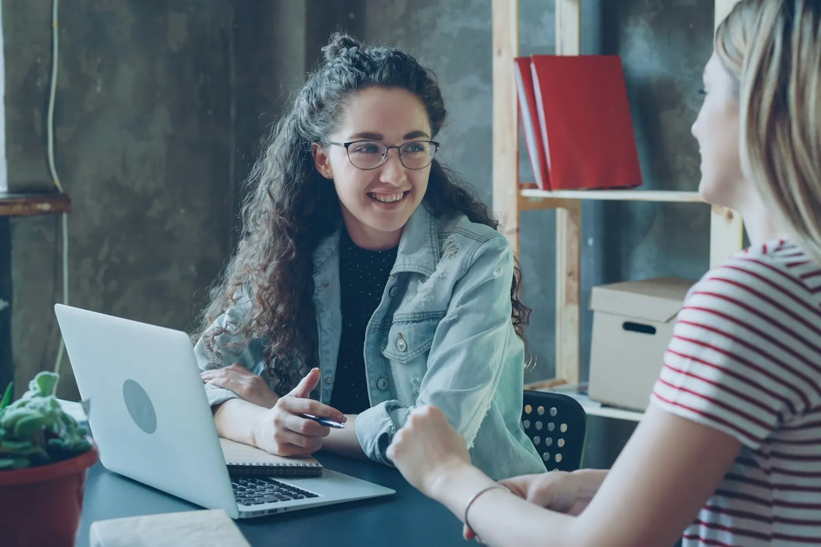 Una profesional conversa con una clienta en una oficina luminosa