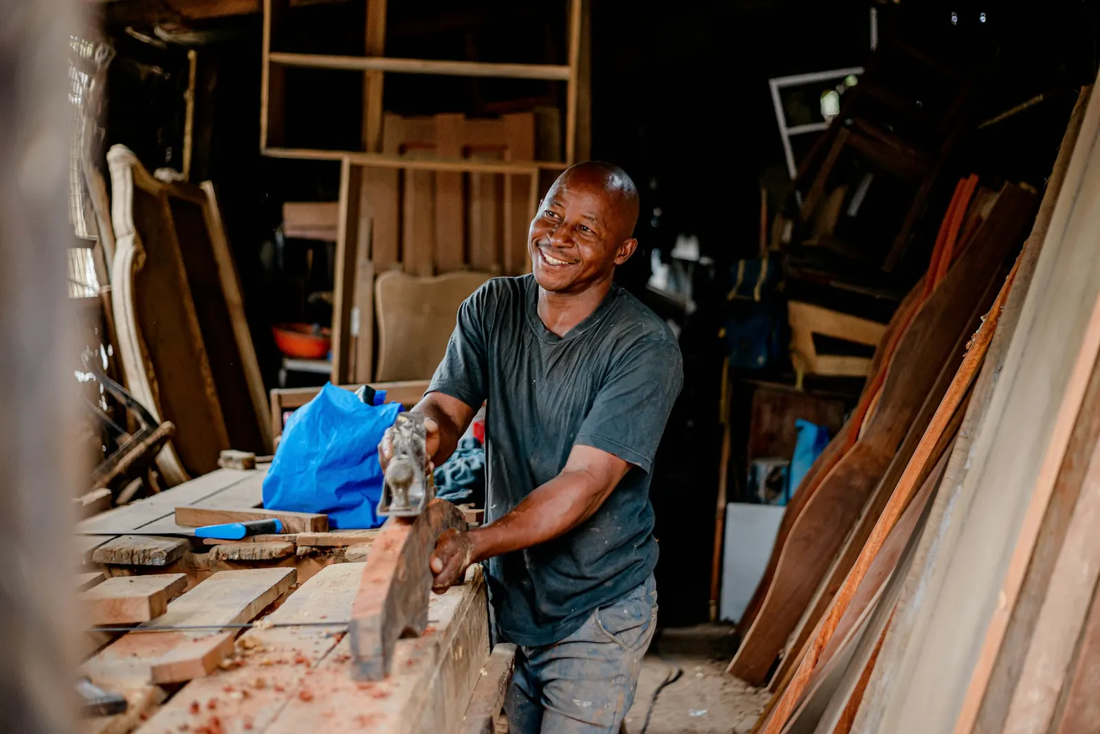 Carpintero sonriendo mientras trabaja la madera en su taller